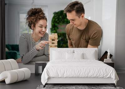 young couple woman and man play jenga game at home on the table Wall mural