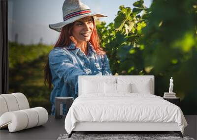 Young woman farmer work and analysis grape leaf in the vineyard Wall mural