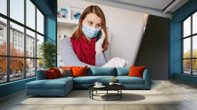 Young woman wearing protective gloves on hands and mask on face working from home or at office work by the table laptop mobile phone call preventing virus spread during epidemic quarantine prevention Wall mural