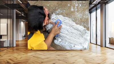 A girl washes the head of a spin mop on concrete Wall mural