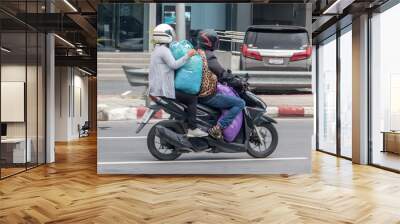 Couple on motorcycle carrying big bags. Transport of large consignments on a moped in the city. Wall mural