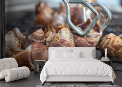 Snails are roasting on the grill. Grilling snails on grate over charcoal. Wall mural