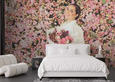 Cheerful lady woman with bouquet of flowers on pink roses floral blossom background Wall mural