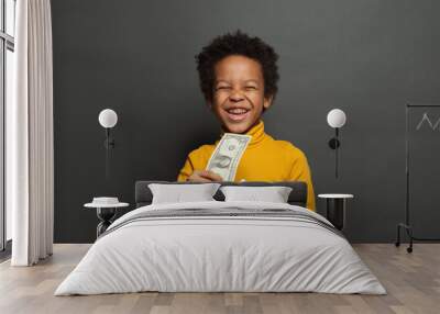 Laughing black child with money box and one us dollar on blackboard background Wall mural