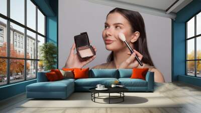 Makeup artist applies blush make-up to a healthy skin of cute female model woman Wall mural