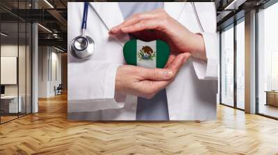 Mexican doctor holding heart with flag of Mexico background. Healthcare, charity, insurance and medicine concept Wall mural