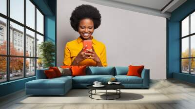 Smiling woman texting on her phone. Happy black model using smartphone, messaging or browsing social networks Wall mural