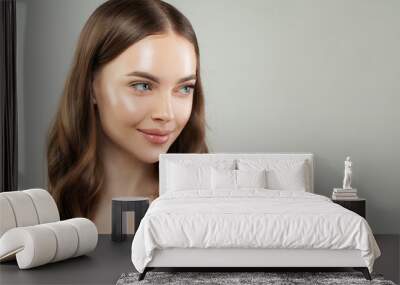 Smiling woman with clear skin and healthy hair on gray background. Beautiful face close up. Skincare and facial treatment concept Wall mural