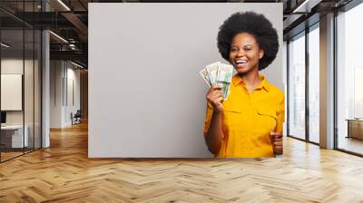 Successful smiling young black woman holding American dollars money on white background Wall mural