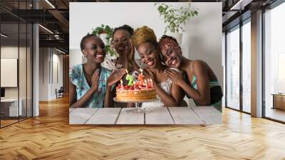 Girl looking at birthday cake surrounded by friends Wall mural