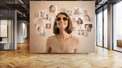 Young woman standing and smiling with many different people's fa Wall mural