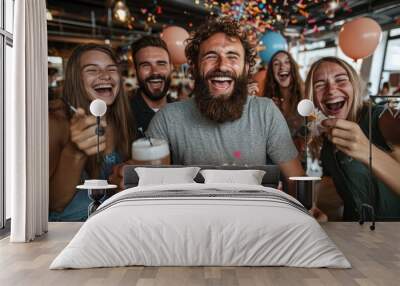 A joyous group of friends is celebrating a birthday with a cake and confetti, enjoying beer while laughing and smiling in a festive setting with colorful balloons. Wall mural