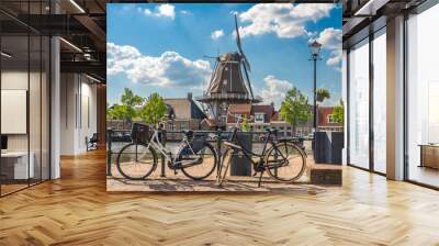 a typical dutch scene with traditional windmill and bikes along the canal in the city of meppel on a Wall mural