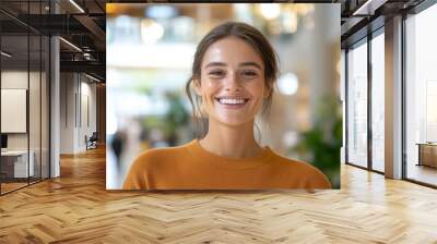 A woman with a radiant smile poses in autumn apparel, creating an elegant scene in a shopping mall filled with soft, ambient lighting and a serene atmosphere. Wall mural