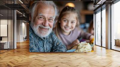 An elderly man and a child are seen bonding over a meal at a family dinner, featuring prominently mashed potatoes and other delicious dishes on the table. Wall mural