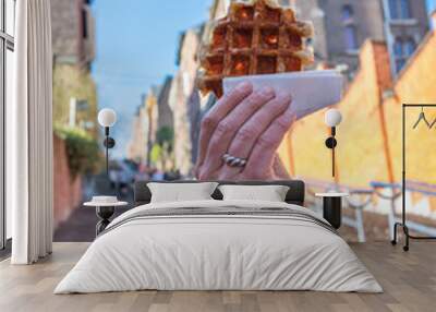 Delicious belgian waffle held in front of blurred background of Montagne de Bueren staircase in Liege, which is a city's top tourist attraction Wall mural