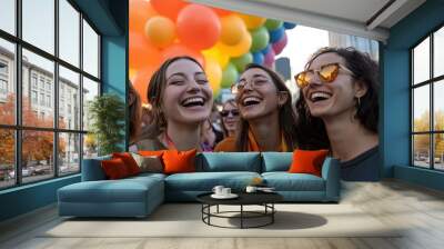 Three women in casual attire share laughter at a pride event, set against a backdrop of colorful balloons, reflecting a joyful and spirited urban atmosphere. Wall mural