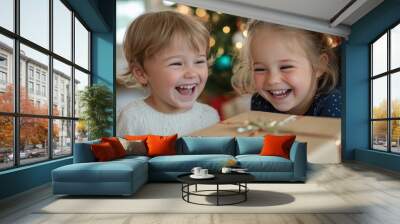 Two little children with glowing smiles share a wrapped gift, their happiness reflecting the warmth and love of the holiday season, epitomizing joy and togetherness. Wall mural