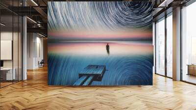 Dreamy surreal landscape with man standing in lake water under starry night sky with star trails. Wall mural