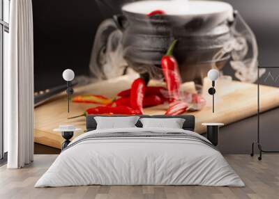 Peppers, beautiful red peppers and a cauldron with smoke over rustic wood, selective focus. Wall mural