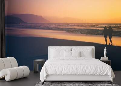 couple walking in the beach at the sunset Wall mural