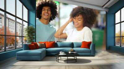 african american man and woman listening to music with mobile phone and earphones Wall mural