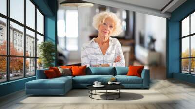 attractive older woman with arms crossed at home Wall mural