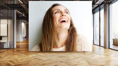 Beautiful middle aged woman laughing against white background Wall mural