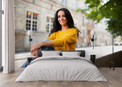 beautiful young brunette woman sitting outside in city Wall mural