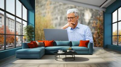 businessman sitting outside working with laptop Wall mural