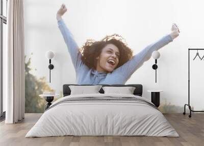 Carefree young woman smiling with arms raised Wall mural