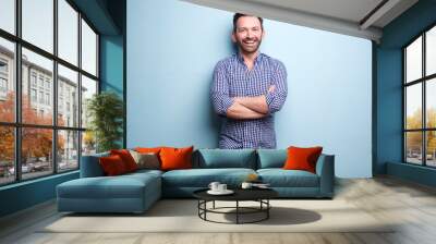 cheerful man with beard posing against blue wall with arms crossed Wall mural