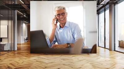 Close up happy businessman sitting in office with laptop and talking with mobile phone Wall mural