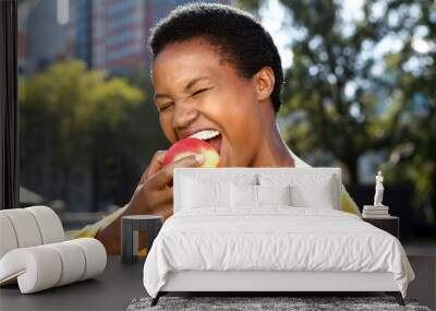 Close up healthy young black woman eating apple outdoors Wall mural