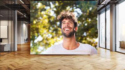 Close up laughing handsome man with beard outside in nature Wall mural