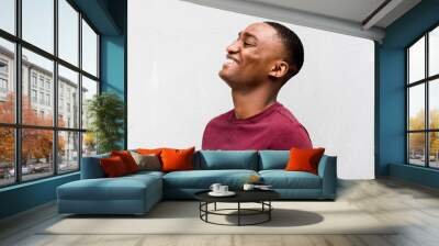 Close up profile happy young African American man laughing against gray background Wall mural