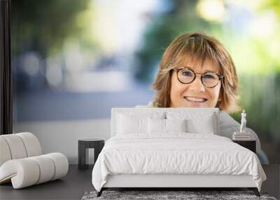 Close up smiling older woman sitting on park bench outside Wall mural