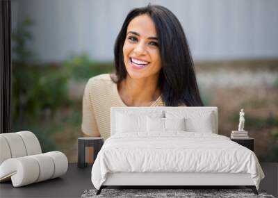 Close up smiling young hispanic woman sitting outdoors Wall mural