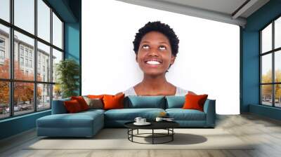 Close up young african woman looking up and smiling on white background Wall mural