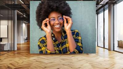 Close up young happy afro woman holding glasses and against green background Wall mural