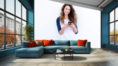 cool young woman smiling with mobil phone against white background Wall mural