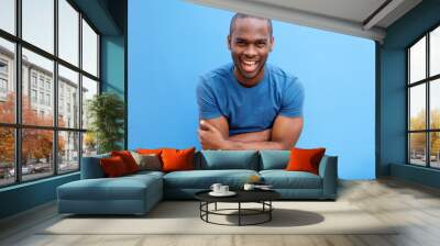 handsome young african american man laughing with arms crossed Wall mural