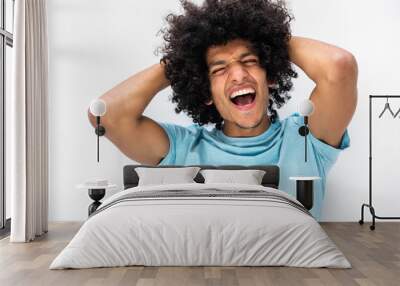 handsome young man with afro hair shouting with hands behind head against white background Wall mural