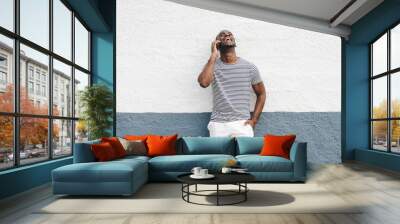 happy african american man in shorts and t-shirt talking with mobile phone Wall mural