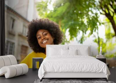 happy black girl with afro smiling outside in city Wall mural