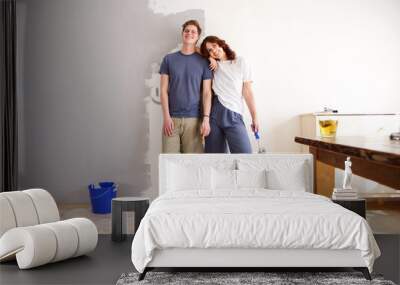 happy boyfriend and girlfriend standing by wall with paint brush Wall mural