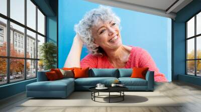 happy older woman smiling by blue wall Wall mural