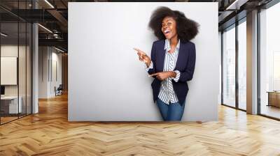 happy young african american woman pointing fingers against gray background Wall mural