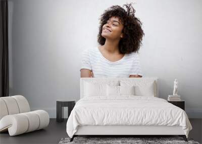 happy young african american woman smiling with arms crossed and looking away against white background Wall mural