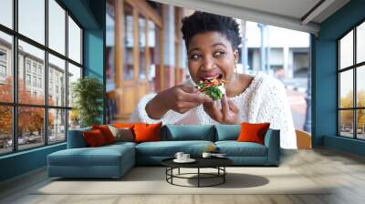 Happy young woman eating pizza at restaurant Wall mural